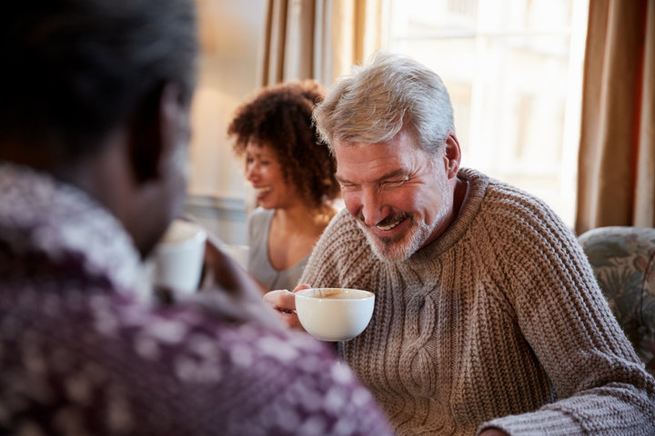 old man laughing with coffee in cafe