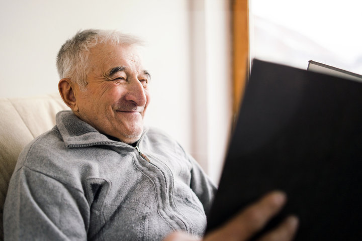 old man smiling at a book