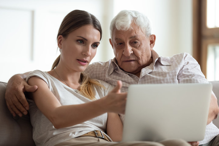 daughter showing her father some care homes on a laptop