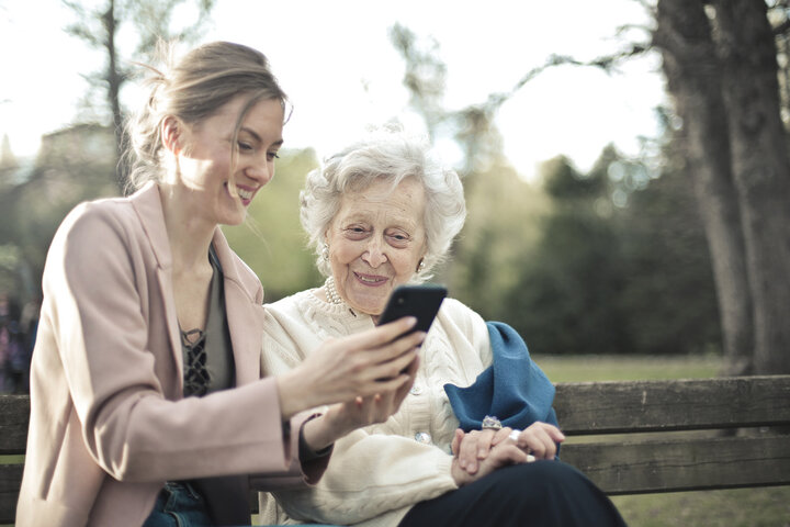 old woman looking at pictures on a phone with family member