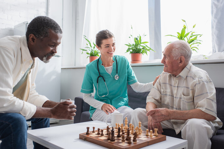 nurse and senior gentlemen next to a chess board